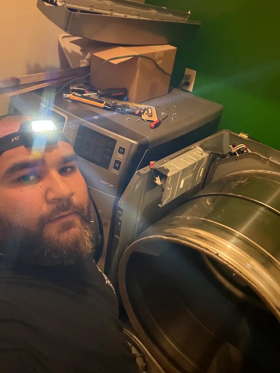 Valve Appliance Repair technician wearing a headlamp repairing a dryer's exhaust duct in a Toronto home.